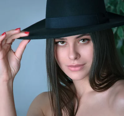 Elegant Woman Holding Black Hat with Red Nails Looking Confidently image