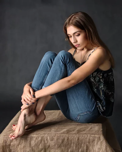 Young Woman Sitting Thoughtfully in Blue Jeans and Floral Camisole image