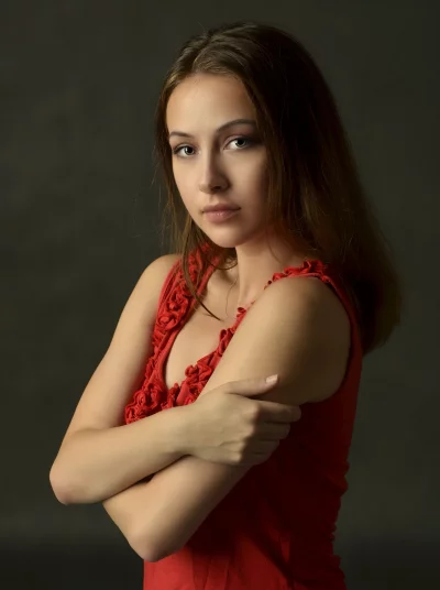 Expressive Woman in Red Top with Crossed Arms and Contemplative Gaze image