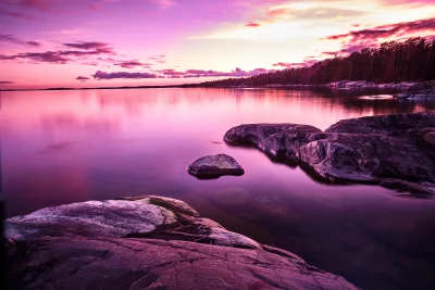 Ethereal Pink and Purple Sunset Over Serene Rocky Lake Landscape image