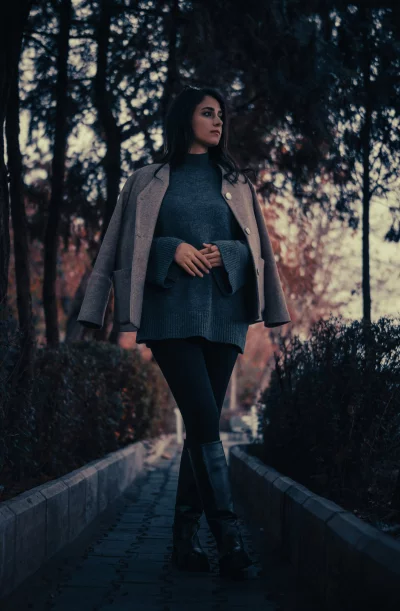 Woman wearing a gray sweater and coat posing in a park