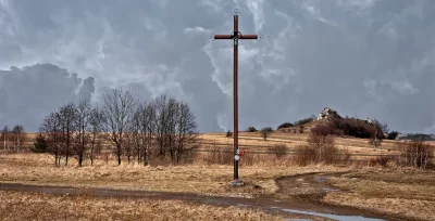 Rustic Calvary Cross in Serene Field Under Dramatic Overcast Sky image