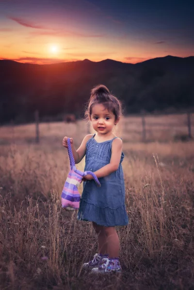 Sweet Toddler Girl with Striped Bag in Golden Sunset Meadow image