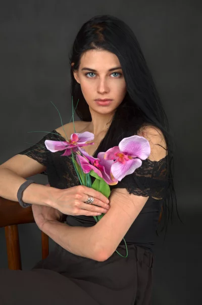 Elegant Woman with Striking Blue Eyes Holding Pink Orchid Flowers image