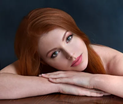 Pensive Redhead Woman with Green Eyes, Serene Portrait on Wooden Surface image