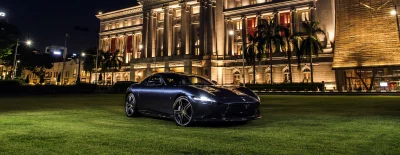 Luxury Dark Blue Ferrari Sports Car on Green Lawn at Night image