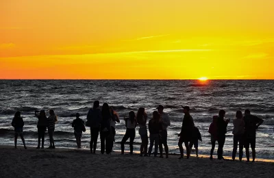 Silhouettes of friends and family watching a breathtaking golden sunset over the tranquil sea image