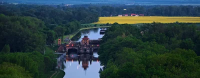 Historic Aqueduct Illuminated at Twilight over Winding River with Vibrant Rapeseed Fields image