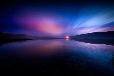 Vibrant Twilight Lake Reflection with Misty Horizon, Light Rays, and Silhouetted Hills image
