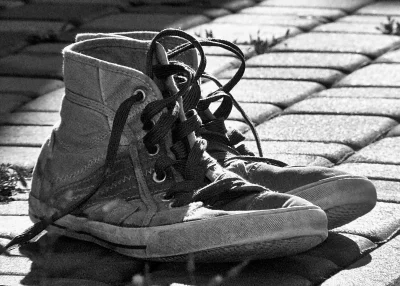 Nostalgic Black and White Worn Canvas High-Top Sneakers on Sunny Pavement image