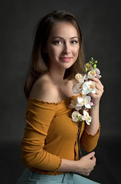 Young Woman Posing with Elegant Orchids, Smiling Candidly for Portrait image
