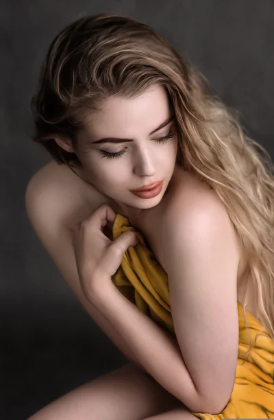 Pensive Young Woman with Golden Drape and Flowing Blonde Hair image