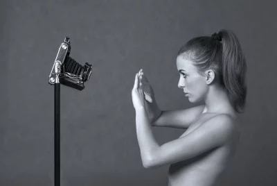 Young Woman Interacting with Vintage Folding Camera in Artistic Studio Portrait image