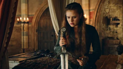 Pensive Woman Holding Ornate Medieval Sword in Candlelit Chamber image