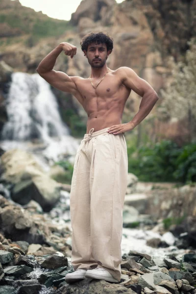 Muscular Young Man Posing Outdoors by Waterfall