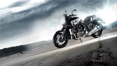 Powerful Black VMAX Motorcycle Parked on Open Road Under Dramatic Cloudy Sky with Sun Flare image
