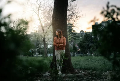 Woman Posing Confidently by a Tree in a Park During Sunset