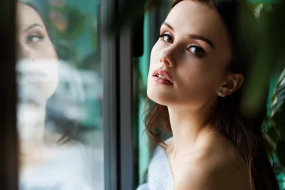 Captivating Young Woman Posing Gracefully by Window with Elegant Reflection image
