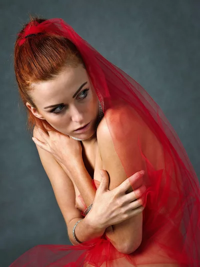 Captivating Redhead Woman with Expressive Eyes Draped in Ethereal Red Tulle image