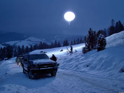 Night Expedition: SUV on Snowy Mountain Road Under Giant Light Balloon image