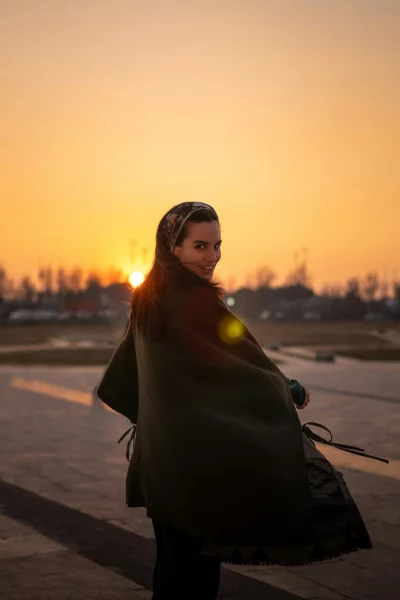 Young woman smiling at sunset wearing a headscarf and shawl