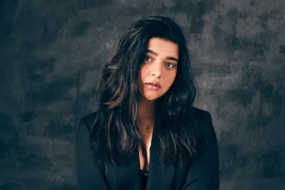 Confident Young Woman in Black Blazer with Piercing Gaze Against Dark Background image