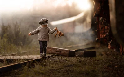 Little Conductor's Adventure: Boy Balancing on Train Tracks with Teddy Bear image