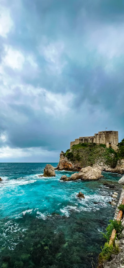 Historic Coastal Fortress Overlooking Vibrant Turquoise Sea Under Dramatic Sky image