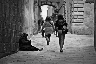Urban Life Contrast: Pedestrians Walk Past Homeless Individual in Historic European Alleyway image