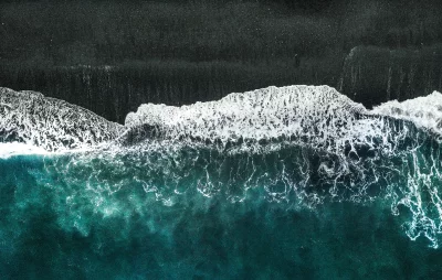 Dramatic Aerial View of Foaming Ocean Waves Breaking on Black Sand Beach image
