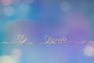 Elegant Golden Wire Art Forming Heart and 'Love' on a Dreamy Blue and Purple Bokeh Background image