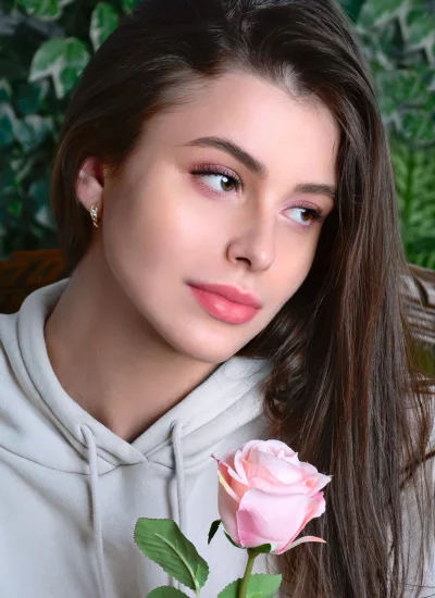 Young Woman Holding Pink Rose with Thoughtful Gaze and Natural Beauty image