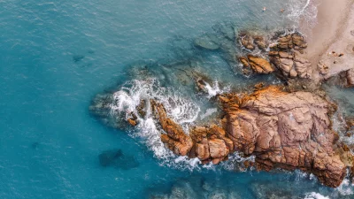 Aerial Drone View of Coastal Beach with People Swimming and Relaxing on Rocky Shore image