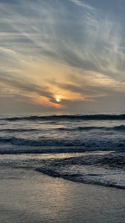 Tranquil beach sunset with gentle waves reflecting warm golden light