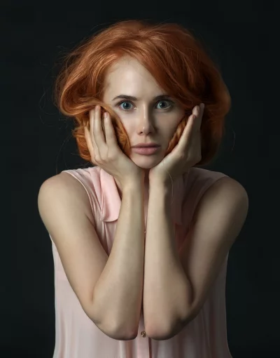 Surprised Redhead Woman with Expressive Blue Eyes and Hands on Face image