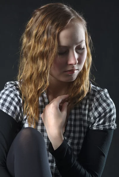 Pensive Young Woman with Wavy Hair in Checkered Shirt Reflecting on Deep Emotions image