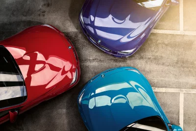 Three Vibrant Luxury Sports Cars Parked on Concrete from an Aerial View image