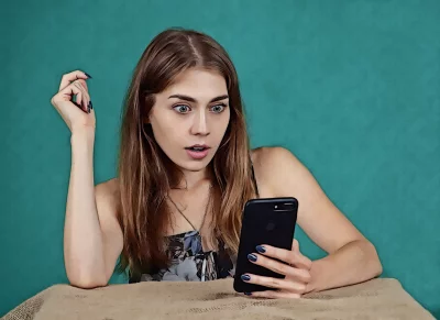 Young Woman Reacting with Shock to Unexpected Smartphone Content image