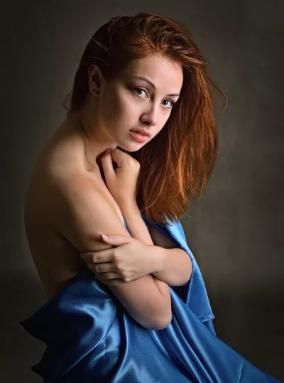 Redhead Woman in Blue Satin with Intense Gaze Studio Portrait image