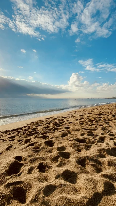 Sandy Beach Footprints with Ocean Waves and Cloudy Sky
