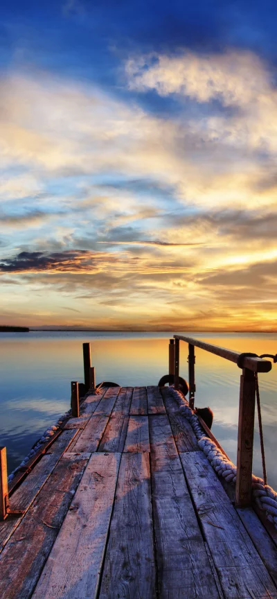 Rustic Wooden Pier Extending into Calm Water at Golden Hour Sunset Reflections image