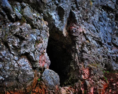 Mysterious Dark Cave Entrance in Rugged Rocky Mountain Wall Landscape image