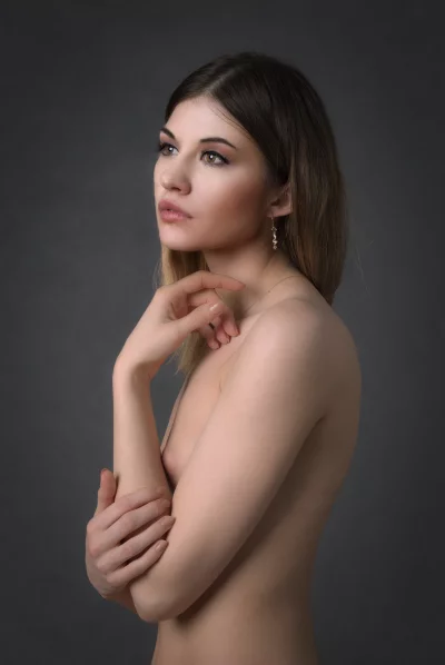 Pensive Bare-Shouldered Woman with Golden Jewelry against Dark Backdrop image