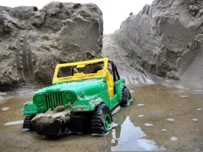Vibrant Green and Yellow Toy Jeep Stuck in Wet Sand Puddle on a Beach image