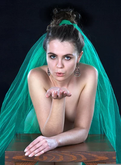 Nude woman in green veil blowing kiss artistic portrait image