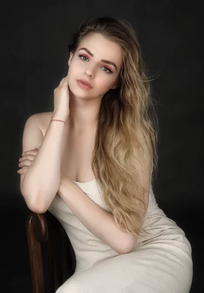 Elegant Young Woman in Ribbed Cream Dress on Wooden Chair image