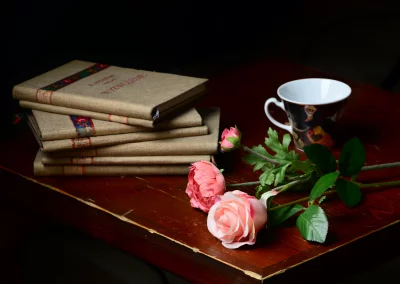 Elegant Still Life with Vintage Linen Books, Pink Roses, Tea Cup on Dark Wood Table image