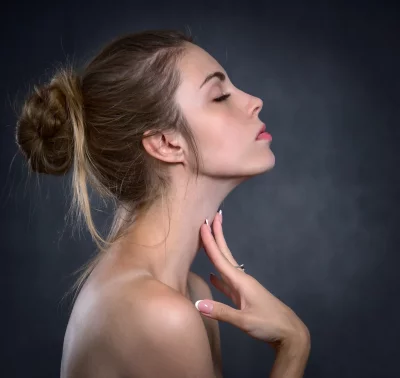 Graceful Young Woman Profile: Closed Eyes, Hand on Neck, Dark Background image