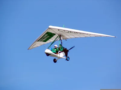 White and Green Ultralight Trike Soaring in Sunny Sky with Pilot image
