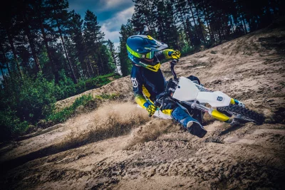 Dynamic Professional Motocross Rider on Husqvarna Dirt Bike Kicking Up Sand on Forest Track image
